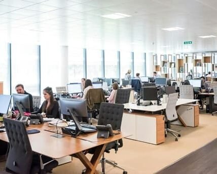 A group of people collaborating at a table, focused on laptops while engaging in knowledge management activities.