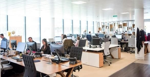 A group of people collaborating at a table, focused on laptops while engaging in knowledge management activities.
